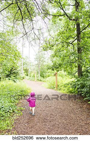 Stock Photograph - Caucasian girl walking on path in forest. Fotosearch