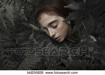 Stock Photograph - Caucasian girl with freckles resting in leaves. Fotosearch