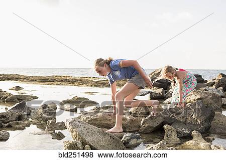 Caucasian girls walking on rocks at beach View Large Photo Image Stock Photo - Caucasian girls walking on rocks at beach. Fotosearch