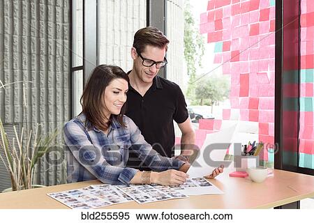 Stock Photography - Caucasian man and woman examining photographs. Fotosearch