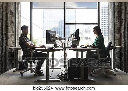 Caucasian man and woman using computers in office View Large Photo Image Picture - Caucasian man and woman using computers in office. Fotosearch