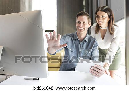 Stock Image - Caucasian man and woman using digital tablet and computer. Fotosearch
