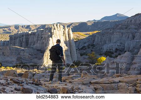 Stock Image - Caucasian man carrying backpack in desert. Fotosearch