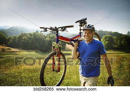 Stock Photography - Caucasian man carrying mountain bike. Fotosearch