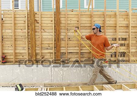 Stock Photo - Caucasian man carrying wire at construction site. Fotosearch