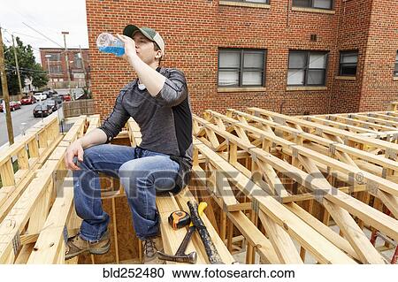 Caucasian man drinking beverage at construction site View Large Photo Image Stock Image - Caucasian man drinking beverage at construction site. Fotosearch