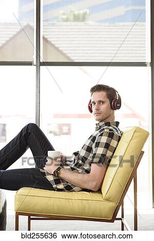 Caucasian man drinking coffee and listening to headphones View Large Photo Image Stock Photograph - Caucasian man drinking coffee and listening to headphones. Fotosearch