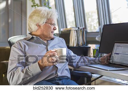 Caucasian man drinking coffee and using laptop View Large Photo Image Stock Image - Caucasian man drinking coffee and using laptop. Fotosearch