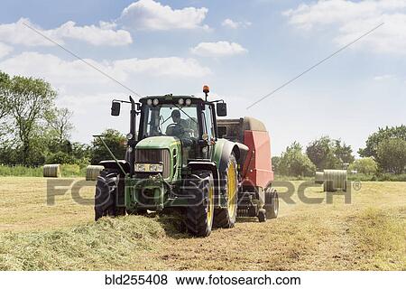 Stock Photo - Caucasian man driving tractor baling hay. Fotosearch