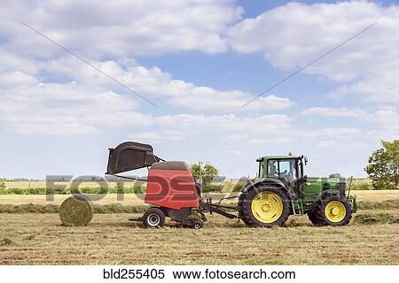 Stock Photography - Caucasian man driving tractor baling hay. Fotosearch