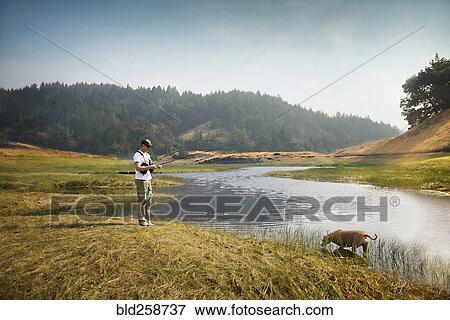 Caucasian man fishing in river near dog View Large Photo Image Stock Photo - Caucasian man fishing in river near dog. Fotosearch