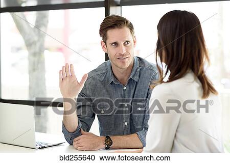 Stock Image - Caucasian man gesturing to woman. Fotosearch