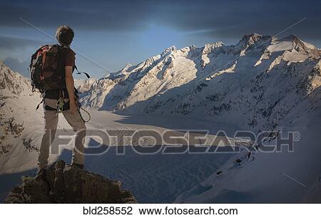 Stock Image - Caucasian man hiking on snowy mountain. Fotosearch