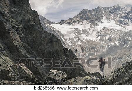 Stock Photograph - Caucasian man hiking on snowy mountain. Fotosearch