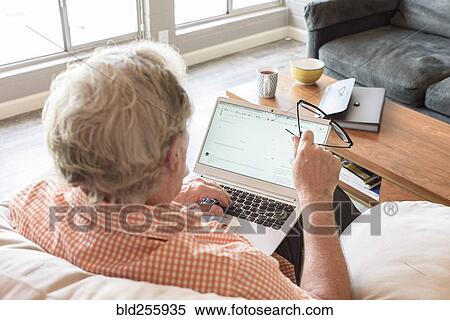 Caucasian man holding eyeglasses using laptop View Large Photo Image Stock Photography - Caucasian man holding eyeglasses using laptop. Fotosearch