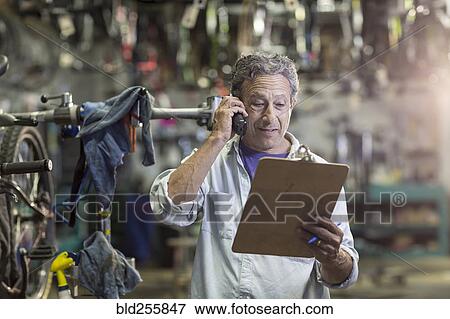 Stock Photo - Caucasian man in bicycle shop talking on telephone. Fotosearch