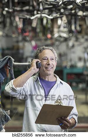 Stock Photograph - Caucasian man in bicycle shop talking on telephone. Fotosearch