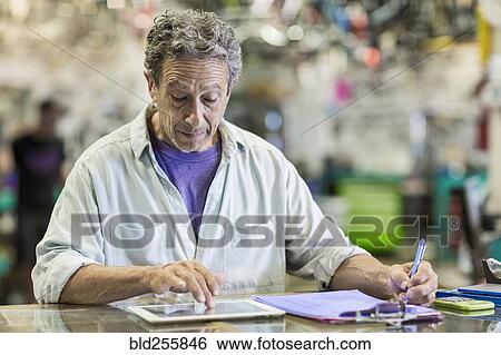 Stock Photograph - Caucasian man in bicycle shop using digital tablet. Fotosearch