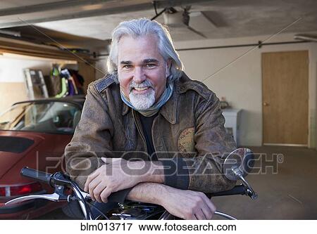 Caucasian man in garage with motorcycle View Large Photo Image Stock Photo - Caucasian man in garage with motorcycle. Fotosearch
