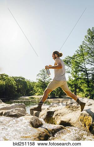 Caucasian man jumping on rocks near river View Large Photo Image Stock Photo - Caucasian man jumping on rocks near river. Fotosearch