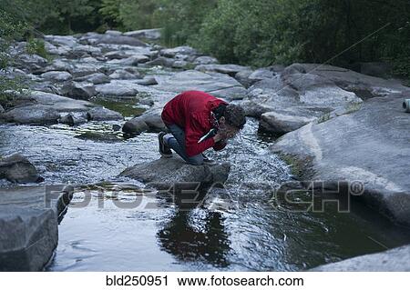 Caucasian man kneeling on rock in river splashing water on face View Large Photo Image Stock Image - Caucasian man kneeling on rock in river splashing water on face. Fotosearch