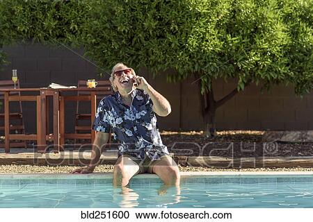 Caucasian man laughing on cell phone with legs in swimming pool View Large Photo Image Stock Image - Caucasian man laughing on cell phone with legs in swimming pool. Fotosearch
