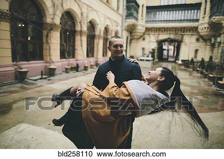 Caucasian man lifting and carrying woman in courtyard View Large Photo Image Stock Image - Caucasian man lifting and carrying woman in courtyard. Fotosearch