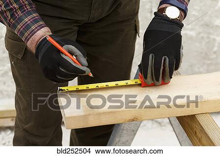 Picture - Caucasian man measuring lumber. Fotosearch