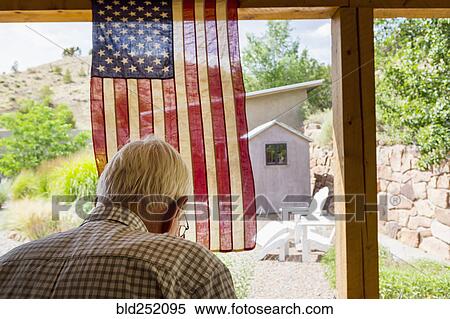 Stock Photography - Caucasian man near American flag in the backyard. Fotosearch