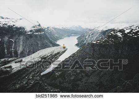 Stock Photography - Caucasian man on cliff admiring scenic view of mountain river. Fotosearch