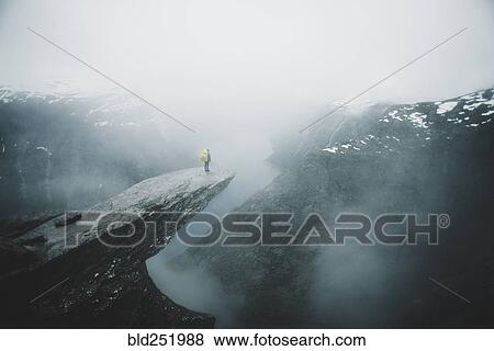 Caucasian man on foggy cliff admiring scenic view of mountain river View Large Photo Image Stock Photo - Caucasian man on foggy cliff admiring scenic view of mountain river. Fotosearch