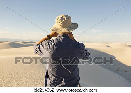 Stock Image - Caucasian man photographing a desert landscape. Fotosearch