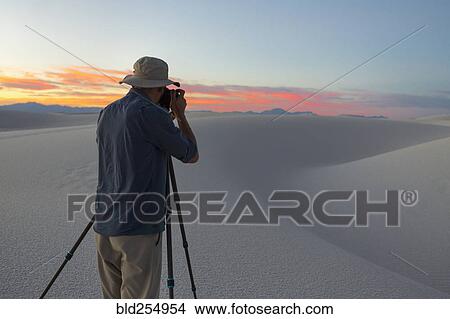 Picture - Caucasian man photographing desert at sunset. Fotosearch