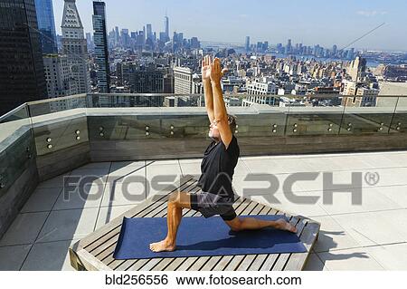Stock Photograph - Caucasian man practicing yoga on urban rooftop. Fotosearch