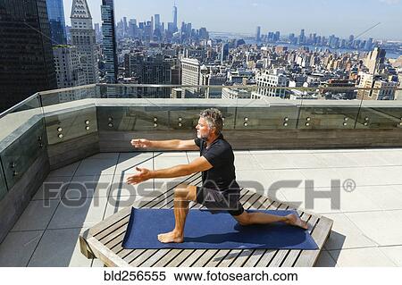 Stock Photography - Caucasian man practicing yoga on urban rooftop. Fotosearch