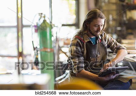 Caucasian man reading a digital tablet in workshop View Large Photo Image Stock Photo - Caucasian man reading a digital tablet in workshop. Fotosearch