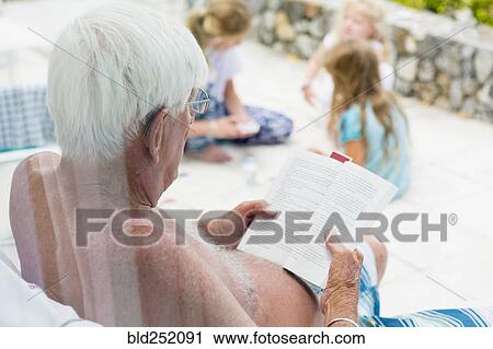 Stock Image - Caucasian man reading book in summer. Fotosearch