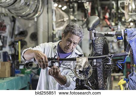 Stock Image - Caucasian man repairing brakes on bicycle. Fotosearch