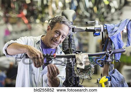 Stock Image - Caucasian man repairing brakes on bicycle. Fotosearch