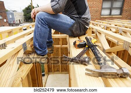 Stock Photo - Caucasian man resting near hammer and tape measure. Fotosearch