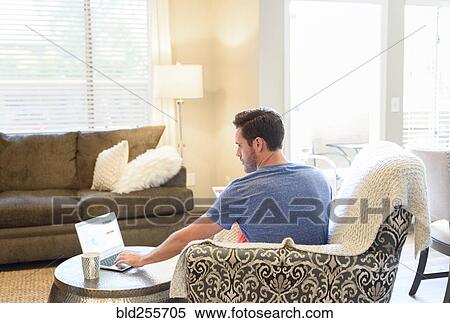 Caucasian man sitting in armchair using laptop and drinking coffee View Large Photo Image Stock Photography - Caucasian man sitting in armchair using laptop and drinking coffee. Fotosearch