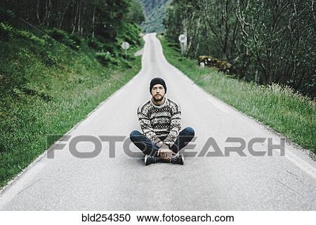 Stock Image - Caucasian man sitting in middle of road. Fotosearch