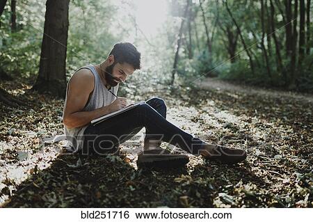 Caucasian man sitting in woods drawing on sketchpad View Large Photo Image Stock Photograph - Caucasian man sitting in woods drawing on sketchpad. Fotosearch