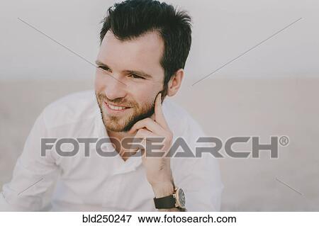 Stock Photo - Caucasian man sitting on beach. Fotosearch
