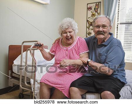 Caucasian man sitting on bed hugging laughing woman View Large Photo Image Stock Photo - Caucasian man sitting on bed hugging laughing woman. Fotosearch