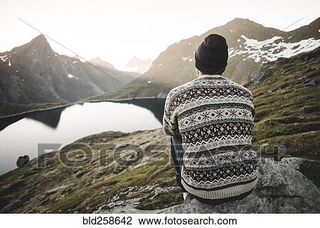 Caucasian man sitting on rock admiring scenic view of mountain lake View Large Photo Image Stock Image - Caucasian man sitting on rock admiring scenic view of mountain lake. Fotosearch