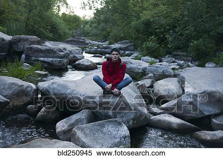 Caucasian man sitting on rock in river View Large Photo Image Stock Photography - Caucasian man sitting on rock in river. Fotosearch