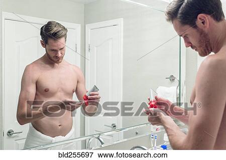 Caucasian man squeezing lotion onto hand in bathroom View Large Photo Image Stock Photo - Caucasian man squeezing lotion onto hand in bathroom. Fotosearch