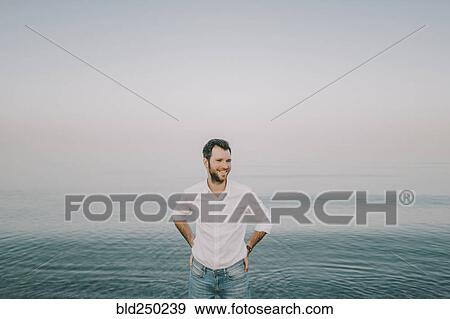 Stock Photo - Caucasian man standing near ocean. Fotosearch