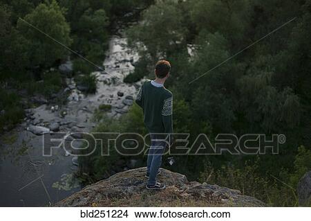 Caucasian man standing on a rock near river View Large Photo Image Picture - Caucasian man standing on a rock near river. Fotosearch
